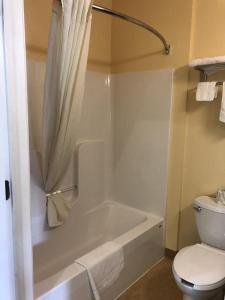 La salle de bains est pourvue d'une baignoire blanche et de toilettes. dans l'établissement Budget Inn Williamsport, à Williamsport