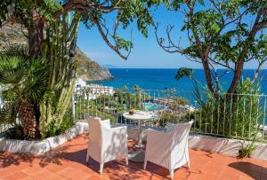 a patio with a table and chairs overlooking the ocean at Hotel San Giorgio Terme in Ischia