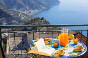 einen Tisch mit einem Buch und Gläsern Orangensaft in der Unterkunft AMORE RENTALS - Residenza Rosalia 1 in Ravello