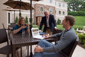 two men and a woman sitting at a table with a laptop at Staybridge Suites Toledo - Rossford - Perrysburg by IHG in Rossford