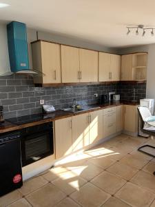 a kitchen with wooden cabinets and a tile floor at Hydrangea House in Kinsale