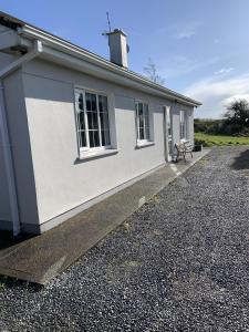 una casa blanca con un banco delante en Hydrangea House en Kinsale