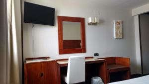 a bedroom with a desk with a mirror and a television at Hotel Hidalgo in Esquivias