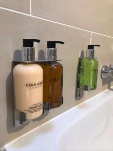 Tres botellas de jabón están sentadas en el lavabo del baño. en Harlow Coach House, en Harrogate