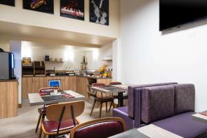 a living room with tables and chairs and a kitchen at Quality Hotel Toulouse Centre in Toulouse