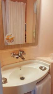 een badkamer met een wastafel en een spiegel bij Premiere Classe Plaisir in Plaisir