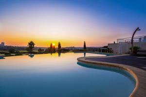 a swimming pool with the sunset in the background at Hôtel Golf Fontcaude in Montpellier