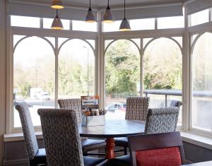 a dining room with a table and chairs in front of a window at Corner House Inn by Greene King Inns in Newcastle upon Tyne