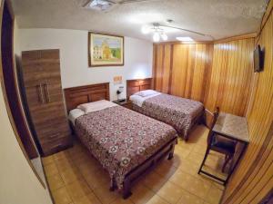 Habitación de hotel con 2 camas y mesa en Hostal Sol y Luna, en Quito