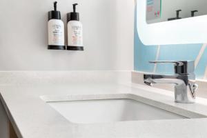 a bathroom sink with two shampoo bottles on the counter at Avid hotels - Oklahoma City Airport by IHG in Oklahoma City +16 photos