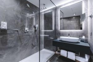a bathroom with a sink and a shower and a mirror at Radisson Blu Hotel, Madrid Prado in Madrid