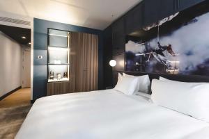 a bedroom with a white bed and a painting of a horse at Radisson Blu Hotel, Madrid Prado in Madrid