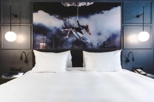 a bed with a white bedspread and a painting on the wall at Radisson Blu Hotel, Madrid Prado in Madrid