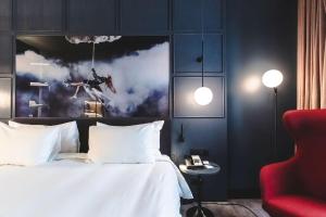 a bedroom with a white bed and a red chair at Radisson Blu Hotel, Madrid Prado in Madrid