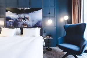 a bedroom with a bed and a blue chair at Radisson Blu Hotel, Madrid Prado in Madrid