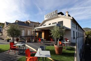 a hotel with tables and chairs on a patio at Hôtel la Capelle Millau in Millau