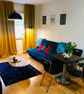 Una sala de estar con un sofá azul y una mesa. en Apartamenty Teatralne, en Gorzów Wielkopolski