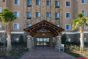 a hotel entrance with palm trees in front of it at Staybridge Suites Tomball, an IHG Hotel in Tomball