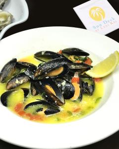 a plate of mussels in a soup with a slice of lemon at Lani Kai Island Resort in Fort Myers Beach