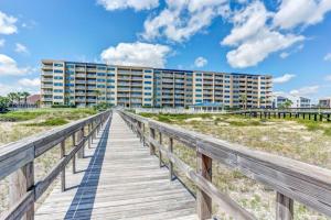 a boardwalk leading to the beach with a building at Amelia By The Sea in Fernandina Beach