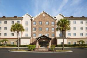Staybridge Suites Tampa East- Brandon, an IHG Hotel في تامبا: مبنى كبير أمامه أشجار نخيل