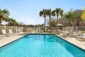 uma piscina com cadeiras e uma cerca e palmeiras em Staybridge Suites Tampa East- Brandon, an IHG Hotel em Tampa