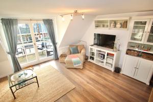 een woonkamer met een bank, een stoel en een televisie bij Appartement Nordseesonne in Wenningstedt