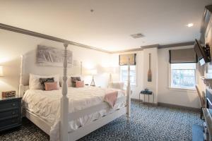 a bedroom with a white bed and two windows at The Whaler's Inn in Mystic