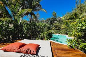 a bed with two orange pillows next to a pool at The Beach Tulum Hotel in Tulum