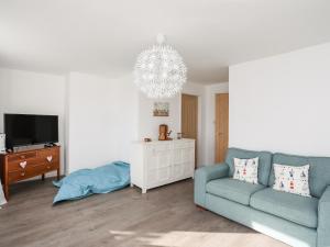 a living room with a blue couch and a tv at Swn y Mor Sound of the Sea in Criccieth