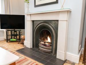 a fireplace with a fire in it in a living room at Spring Bank Cottage in Highpeak Junction