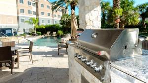 a outdoor kitchen with a grill and a pool at Staybridge Suites Houston-NASA Clear Lake by IHG in Webster