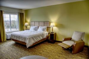 a bedroom with a bed and a chair and a window at Candlewood Suites - Austin North by IHG in Austin