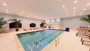 a large swimming pool in a building with tables and chairs at Staybridge Suites Ann Arbor - Research Parkway, an IHG Hotel in Ann Arbor
