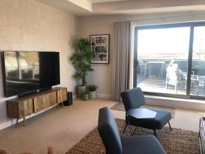 uma sala de estar com uma televisão de ecrã plano e cadeiras em Chapel Penthouse em York