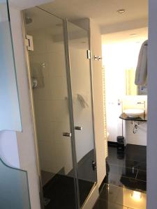 bagno con doccia in vetro e lavandino di Hotel Schmales Haus a Ulma