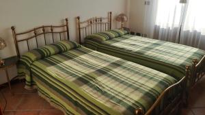 2 letti in una camera da letto con lenzuola verdi e bianche di Casa Gardenia a Oggebbio