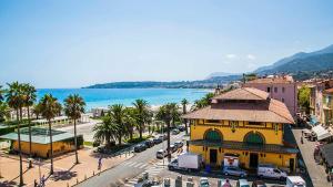 a city with a yellow building and a street with cars at Charmant 2 Pièces Vue sur Mer et MONTE-CARLO à ROQUEBRUNE CAP MARTIN in Roquebrune-Cap-Martin
