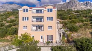 an apartment building on a hill with mountains in the background at Apartments Galic in Podgora
