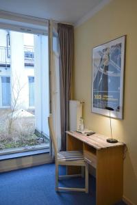 a desk with a lamp and a chair next to a window at ALPHA Hotel Garni in Hamburg