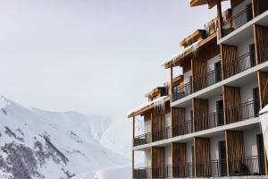 a hotel with snow covered mountains in the background at GeoGraphy Hotels in Gudauri