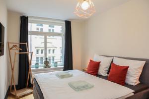 Schlafzimmer mit einem Bett mit roten Kissen und einem Fenster in der Unterkunft Sleepwell Apartment - Klostersuite in Leipzig