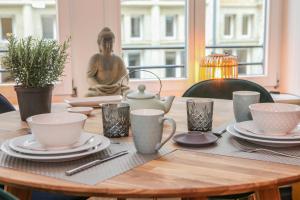 una mesa de madera con platos y tazas y una estatua en Sleepwell Apartment - Klostersuite en Leipzig