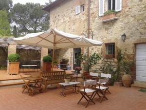 a patio with an umbrella and chairs and a bench at Podere San Quirico in Castelnuovo Berardenga
