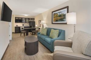 uma sala de estar com um sofá azul e uma cozinha em Candlewood Suites - Charlotte - Arrowood, an IHG Hotel em Charlotte