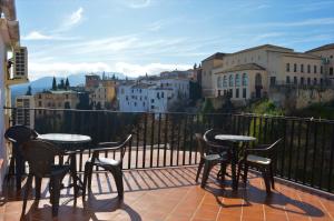 a balcony with tables and chairs and a view of a city at Casa Duende del Tajo in Ronda