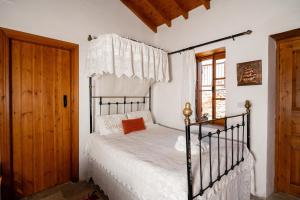 a bedroom with a bed with white sheets and a window at Constantias stone houses in Lofou