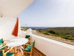 a balcony with a table and chairs and an umbrella at Duplex Son Parc Vistas Costa Norte in Es Mercadal