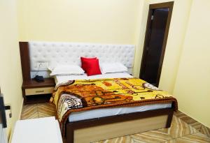 ein Schlafzimmer mit einem Bett mit einem roten Kissen in der Unterkunft Hotel vinayak inn in Haridwar