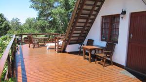 a wooden deck with chairs and tables on a house at Heatherhill Chalet - Sea and mountain views in Keurboomstrand